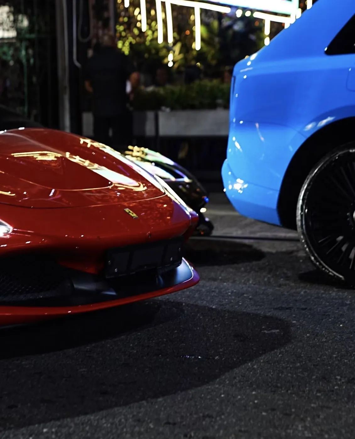 Detalle de un Ferrari rojo junto a un Rolls-Royce azul