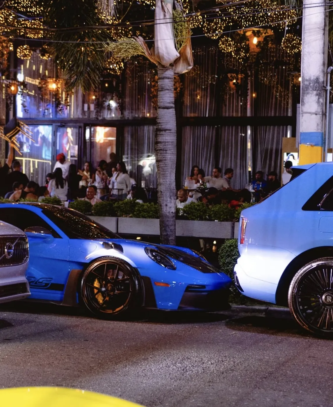 Porsche GT3 RS azul y Rolls-Royce Cullinan frente a la terraza de Dial